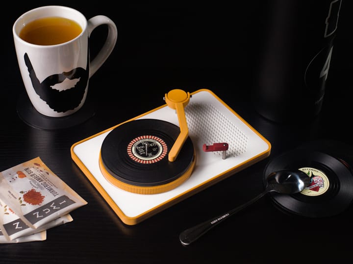 Vinyl Coaster Turntable on a dining table with mug, tea bags, spoon, and a thermos.