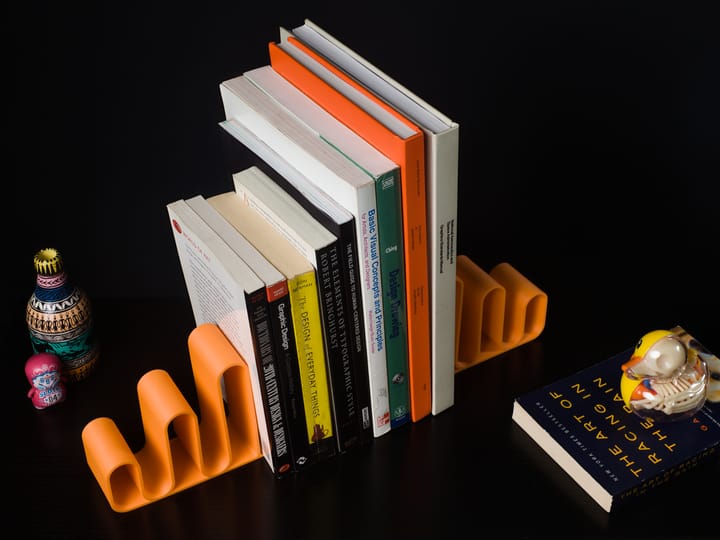 Vertically aligned books with bookends supporting them and various figures and vases laid out on a desk